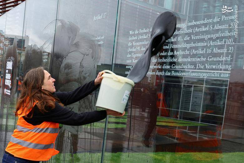 در جریان اعتراض به تغییرات آب و هوایی یک زن معترض، مایع سیاه رنگی را روی یک اثر هنری منقش به متن ماده 49 قانون اساسی که در مورد حقوق اساسی است می پاشد./ برلین - آلمان